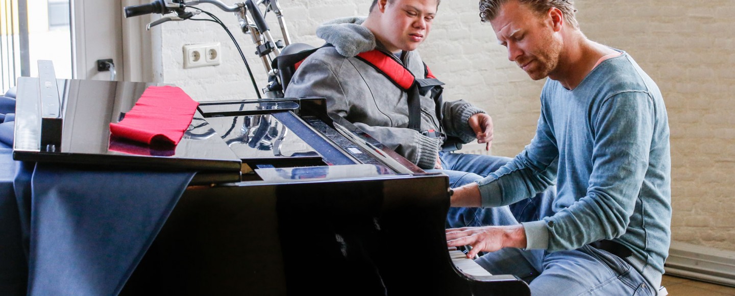 Begeleider speelt piano voor gehandicapte man